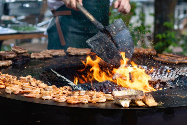 Feuerring mit verschiedenen Fisch und Garnelenteilen die gegrillt werden.