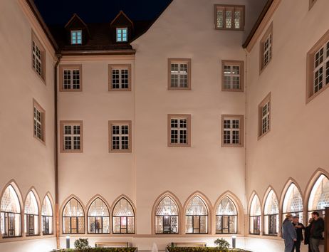 Innenhof des Augustinermuseums bei Nacht mit beleuchteten Fenstern und einem zentralen Brunnen.