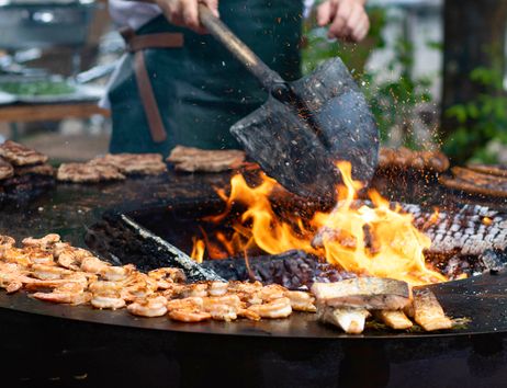 Feuerring mit verschiedenen Fisch und Garnelenteilen die gegrillt werden.